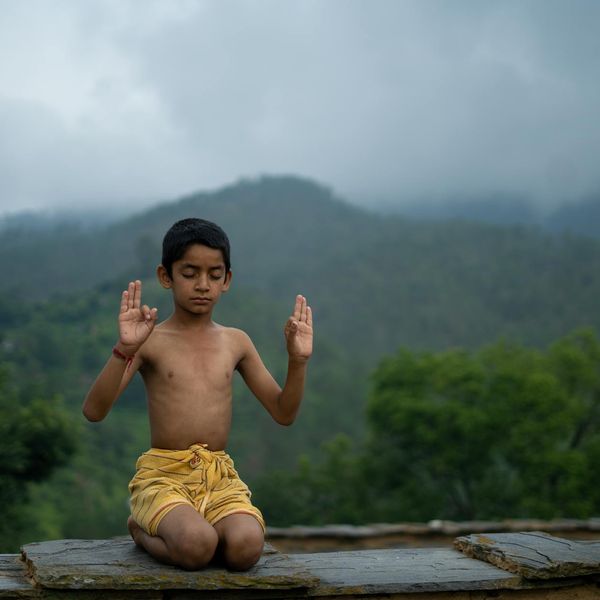 Person meditating in a lotus position against a simple background.
